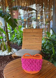 an orange and pink bag sitting on top of a wooden table next to a chair