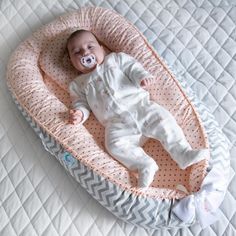 a baby laying on top of a bed with a pacifier in it's mouth