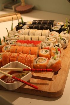 sushi platter with chopsticks and dipping sauce on wooden cutting board in kitchen area