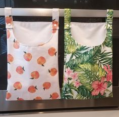 two aprons hanging from the side of a microwave oven with fruit printed on them