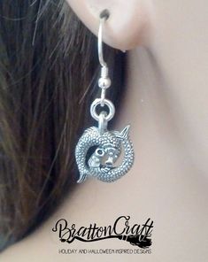 "I love these adorable Silver Pisces Earrings! The 3D charm has so much detail with two fish with sucker style mouths, eyes, scales, back fins and tail fins. It measures 1/2 inches long and 5/8 inches wide from tail fin to tail fin. It's made in the USA using lead free pewter. The French earwire is sterling silver with a coil and bead accent. Plastic earring backs are included. These lovely are ready to ship and will arrive in a gift box. View other BrattonCraft Astrology Jewelry here: https://w Symbolic Nickel-free Plug Earrings As Gift, Symbolic Nickel-free Plug Earrings For Gifts, Metal Symbolic Hypoallergenic Earrings, Symbolic Single Metal Earring, Symbolic Nickel-free Drop Plug Earrings, Nickel-free Symbolic Drop Plug Earrings, Symbolic Metal Dangle Earrings, Symbolic Dangle Plug Earrings For Pierced Ears, Pisces Earrings