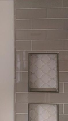 a bathroom with white tile and two square mirrors on the wall next to each other