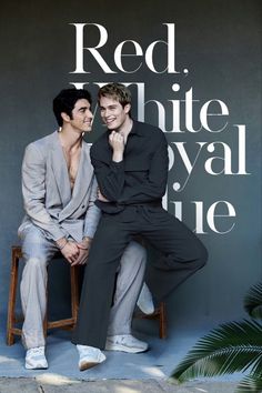 two men sitting on a chair in front of a wall with the words red, white, royal blue