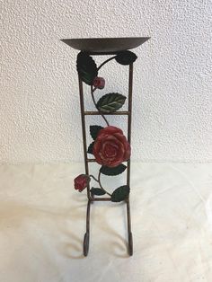 a metal plant stand with red roses on it