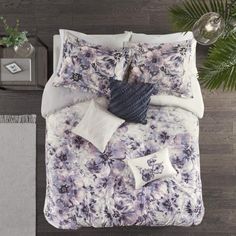 an overhead view of a bed with purple flowers on it and white pillows in the middle