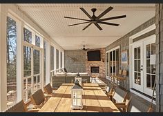 an outdoor dining area with wooden table and chairs, ceiling fan and large patio windows