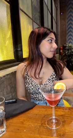 a woman sitting at a table with a drink