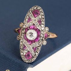 A classic Edwardian dinner ring, studded with rose cut diamonds and calibre cut pink sapphires. She spans across the top of the finger beautifully, giving you big flashes of color from the sapphires and subtle sparkle from those rose cuts. A beautiful ring to add a juicy pop of color to your collection of rings! Platinum & 18kt yellow gold Size 6.5 & resizable Center is estimated to be J/K color & Si2/I1 clarity Surrounding diamonds are estimated to be H/K color & VS/SI clarities Rubies are esti Pink Oval Multi-stone Ruby Ring, Pink Multi-stone Diamond Ring, Luxury Pink Sapphire Ring With Rose Cut Diamonds, Fine Jewelry Pink Ruby Ring With Single Cut Diamonds, Oval Pink Sapphire Diamond Ring With Accents, Pink Sapphire Multi-stone Ring With Diamond, Pink Marquise Cut Diamond Ring, Pink Ruby Diamond Ring With Multi-stones, Anniversary Pink Sapphire Ring With Rose Cut Diamonds