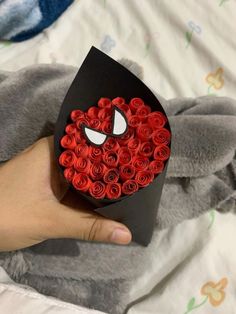 someone is holding a box with red roses in the shape of a spiderman's face