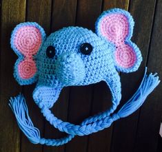 a crocheted hat with an elephant's head and ears is hanging on a wooden wall