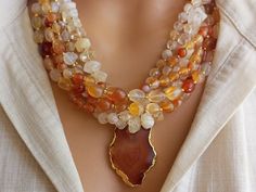 Meet our elegant Quartz - Agate Beaded Necklace, a collection of unique handcrafted jewelry that is sure to attract attention! This eye-catching necklace creates a striking visual with large gem stones in different shades of orange. Perfect as a gift for a beloved mother or wife, this statement chunky multi-strand natural stone summer accessory will add a bohemian touch to any outfit. CARE INSTRUCTIONS: To keep your necklace looking its best, avoid exposing it to harsh chemicals or excessive moisture. To clean, wipe gently with a soft, damp cloth. To prevent any damage or tarnishing, store your necklace in a cool, dry place when not in use. DIMENSIONS: - Length: 18 inches. - Pendant Size: 1 inches. - Beads: 4-12 mm. ABOUT ORDERS: * All orders will be shipped to the shipping address you pro Unique Handcrafted Jewelry, Bead Making, Orange Agate, Necklace Chunky, Gem Stones, Crystal Quartz, Agate Beads, Summer Accessories, Agate Gemstone