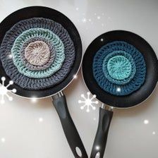 two crocheted frying pans sitting side by side