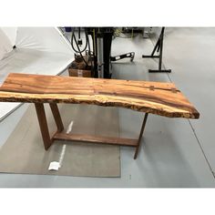 a wooden bench sitting on top of a floor next to a metal object in a room