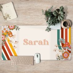 a computer mouse pad with the word sarah on it next to a keyboard and plant