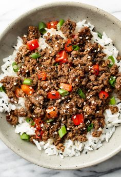 a white bowl filled with ground beef and rice on top of a marble countertop