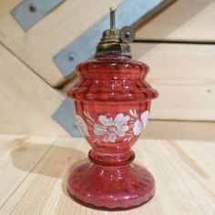 a red glass vase sitting on top of a wooden table