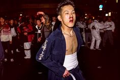 a young man with blood on his face and chest standing in front of a group of people