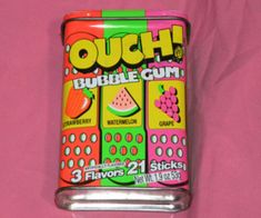 a can of bubble gum sitting on top of a pink surface with the words ouch in it