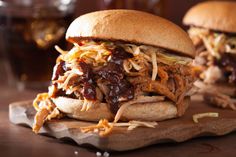 a pulled pork sandwich sitting on top of a wooden cutting board