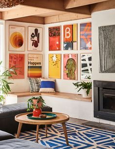 a living room filled with furniture and art on the wall above a wood burning fire place