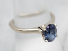 This is a well-proportioned ring, classic and sophisticated. The brightly polished sides have a great heft to them, and this is comfortable on the finger, with a rich feel. We've set the center with a bright blue Ceylon sapphire that has glittering navy and cobalt highlights and plenty of sparkles.Metal: 14K White GoldGem: Sapphire 1.85 CaratsGem Measurements: 6.2 x 8.6 mm, OvalAccents: Diamond .01 Carats, J in Color, I in ClarityRing Size: 9Marks: "14Kt" Stamped on the inside band Classic Sapphire Ring In 14k White Gold, Classic Sapphire Birthstone Ring, Classic Sapphire Halo Ring, Classic Oval Sapphire Ring With Polished Finish, Modern Round Sapphire Ring For Formal Occasions, Modern Sapphire Ring For Formal Occasions, Timeless Polished Sapphire Ring, Modern Oval Tanzanite Sapphire Ring, Elegant Sapphire Ring With Tanzanite And Polished Finish