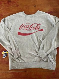 Vintage Coca Cola Crewneck Sweatshirt  Size Large  See pics for measurements  Classic Gray with classic red logo of this iconic brand  Simple and understated  Fine condition  Quick shipping.   We ship same or next day with USPS mail  We are a small family business and we appreciate your purchase, Godspeed ! Classic Cotton Sweatshirt With Letter Print, Retro Crew Neck Pre-shrunk Top, Classic Crew Neck Tops With Letter Print, Classic Crew Neck Sweatshirt With Letter Print, Classic Crew Neck Top With Logo Print, Casual Red Tops With Lettering, Retro Crew Neck Top With Lettering, Vintage Crew Neck Tops With Lettering, Retro Crew Neck Solid Tops