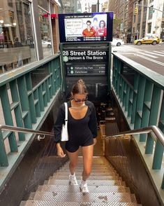 a woman is walking down the stairs in front of a subway station sign that reads 28 street station