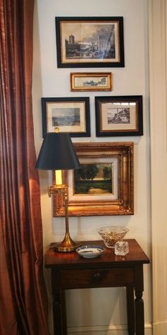 a table with a lamp and pictures on the wall