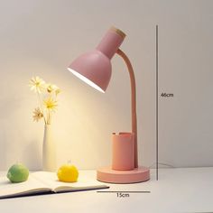 a pink lamp sitting on top of a table next to a book