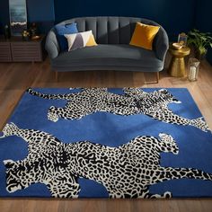 a living room with blue walls and leopard rugs on the wooden floor, along with a gray couch