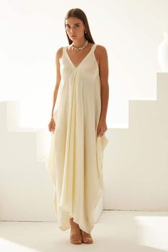 Cream modal asymmetrical maxi dress with a V neckline. - Aza Fashions Elegant Summer Maxi Dress With Asymmetrical Neckline, Elegant Beach Maxi Dress With Asymmetrical Neckline, Elegant Asymmetrical Neckline Maxi Dress For Beach, Chic Flowy Sleeveless Asymmetrical Dress, Summer Flowy Floor-length V-neck Dress, Elegant Asymmetrical Maxi Dress For Summer, Chic Asymmetrical Neckline Maxi Dress For Vacation, Elegant Asymmetrical Midi Dress For Vacation, Sleeveless Viscose Maxi Dress For Evening