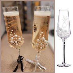 two champagne flutes with pearls in them on a table