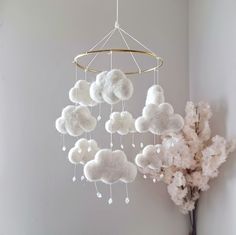 a white cloud mobile hanging from the ceiling next to a vase with flowers in it