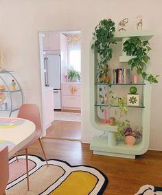 a living room filled with furniture next to a dining table and bookshelf covered in plants