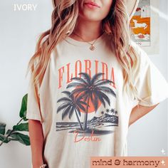 a woman wearing a white shirt with a palm tree on it and the words florida written in orange