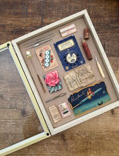 a shadow box filled with assorted items sitting on top of a wooden table next to a pen