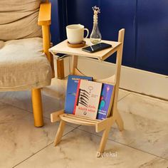 a small table with books and a cup on it in front of a blue wall