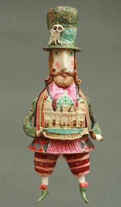 a ceramic figurine with a hat and mustache on it's head, standing in front of a gray background