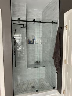 a walk in shower sitting next to a white door and window with black trim on the walls