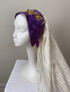 A new professional quality Renaissance Medieval Tudor Victorian Elizabethan ladies' hat. This hat has a purple brocade crown embellished with a gold motif and pearl back crown trim. A cascading 24" back cream coverlet. Matching ribbon tie holds this regal cap in place. New not worn. Crown is 17 1/2 " by 4 1/2". Crown lined with security comb. A great item for your next theme party, stage production or special occasion. Sales final. Mardi Gras Costume Headpiece With Tall Crown, Tall Crown Headpiece For Mardi Gras Costume, Fitted Costume Hat With Tall Crown, Fitted Tall Crown Costume Hats, Fitted Costume Hats And Headpieces For Cosplay, Traditional Fitted Costume Hats And Headpieces, Adjustable Costume Headpiece For Mardi Gras, Mardi Gras Costume Headpiece With Adjustable Fit, Adjustable Purple Hat For Costume