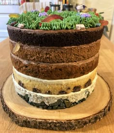 a layered cake sitting on top of a wooden plate covered in frosting and grass