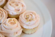 cupcakes with pink frosting and gold sprinkles on a white plate