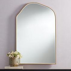 a mirror sitting on top of a dresser next to a vase with flowers