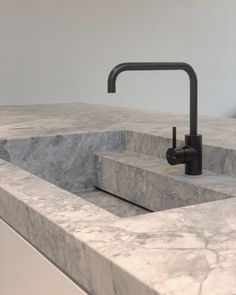 a marble sink with a black faucet in the middle