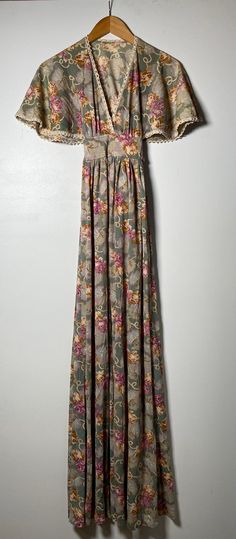 "This 1970's dress is simply gorgeous! In a light olive green color that can at times appear gray, this maxi dress is bohemian and beautiful in style! It appears to have had a tag at one point, which has been cut out. It is closest to a size small, but here are the exact measurements taken lying flat and doubled: Shoulders: 13 1/2 inches Chest: 32 inches Waist: 28 inches Hips: 40 inches Shoulders to Hem: 55 inches This dress ties at the back and has a side zipper. The front neckline plunges into Vintage Flowy Maxi Dress For Summer, Flowy Vintage Maxi Dress For Summer, Green Flowy Vintage Maxi Dress, Vintage Green Floor-length Maxi Dress, Vintage Floor-length Maxi Dress For Spring, Vintage Green Maxi Dress For Summer, Green Vintage Maxi Dress For Summer, Bohemian Gray Maxi Dress For Summer, Vintage Floral Print Floor-length Maxi Dress