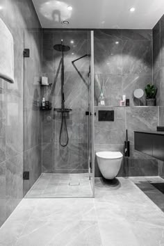 a modern bathroom with grey marble walls and flooring, including a walk in shower