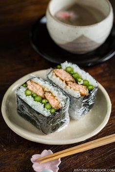 two sushi rolls on a plate with chopsticks next to it