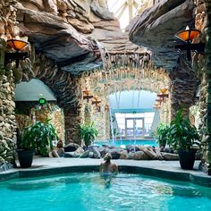 an indoor swimming pool surrounded by stone walls and potted plants on either side of the pool