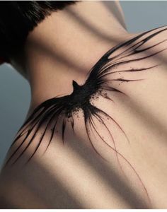 the back of a woman's neck with black feathers on it