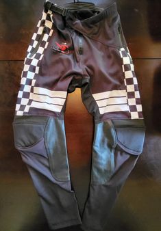 Made for comfort and function, the Checkered Moto Pants are a rider's best friend on the trails. Technical Features + Two side zipper front pockets - yes, actual pockets! + Mesh Comfort Liner + Backside stretch panels to relax waist line + Leather leg panels to reinforce from boot friction + Ratcheting closure waist belt for adjustability Pre-shaped knee to accommodate most shaped guards Fitted Black Pants With Functional Pockets, Casual Pants With Pockets For Biker Events, Fitted Biker Bottoms For Outdoor, Fitted Bottoms With Pockets For Motorcycling, Fitted Motorcycling Pants With Pockets, Sports Pants With Zip Fly In Black, Black Sports Pants With Reflective Details, Sports Black Pants With Reflective Details, Fitted Cargo Sports Pants